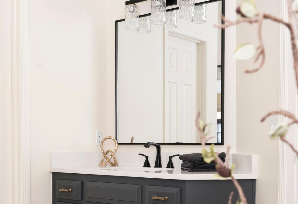 Modern primary bathroom with dark grey vanity, large rectangular mirror, and white marble countertops