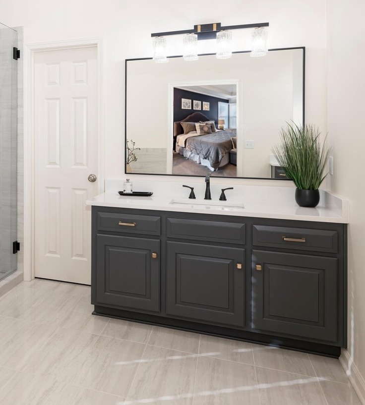 Modern primary bathroom with dark grey vanity, large rectangular mirror, and white marble countertops