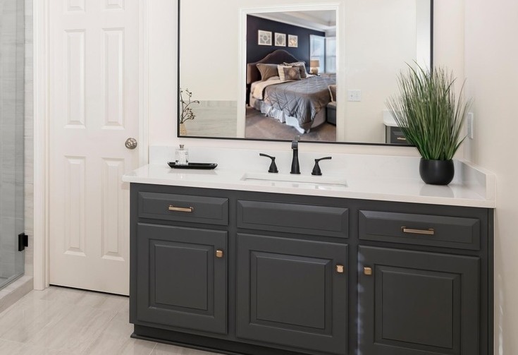 Modern primary bathroom with dark grey vanity, large rectangular mirror, and white marble countertops