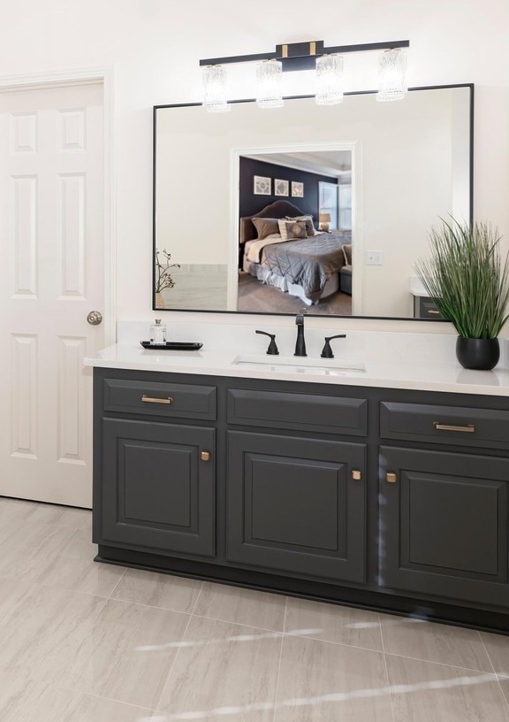 Modern primary bathroom with dark grey vanity, large rectangular mirror, and white marble countertops